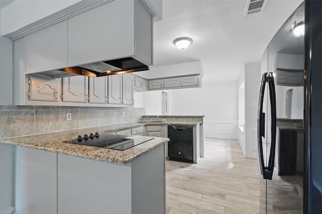 829 Hunters Creek Dr, Desoto, TX 75115 - kitchen featuring visible vents, light wood-style floors, black appliances, a peninsula, and wainscoting