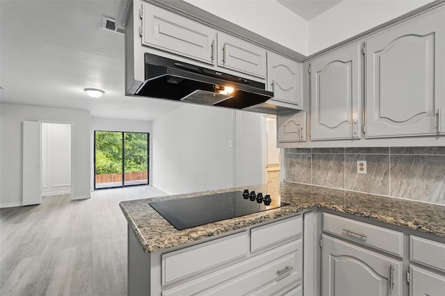 829 Hunters Creek Dr, Desoto, TX 75115 - kitchen with black electric stovetop, under cabinet range hood, backsplash, light wood finished floors, and a peninsula