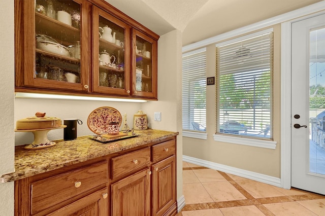 bar featuring light tile patterned flooring, a healthy amount of sunlight, and baseboards