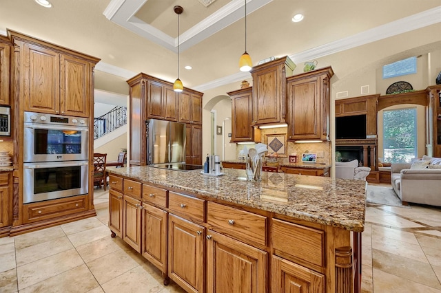 kitchen featuring light stone counters, crown molding, stainless steel appliances, open floor plan, and backsplash