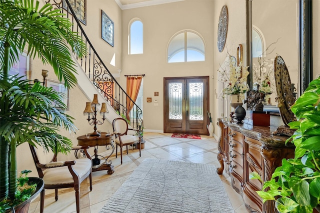 entryway with a high ceiling, light tile patterned flooring, crown molding, stairs, and baseboards