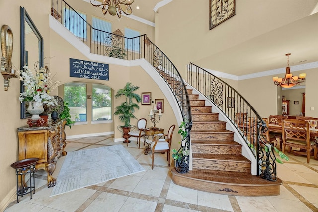 stairway with a chandelier, baseboards, a high ceiling, and crown molding