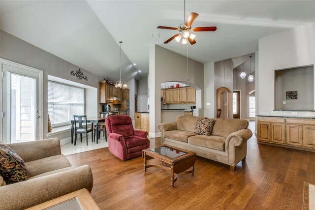 living room featuring dark wood-style floors, high vaulted ceiling, arched walkways, and a ceiling fan