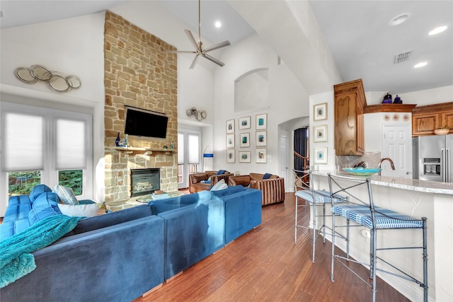 3040 N Camino Lagos, Grand Prairie, TX 75054 - living room with arched walkways, wood finished floors, a stone fireplace, visible vents, and a ceiling fan