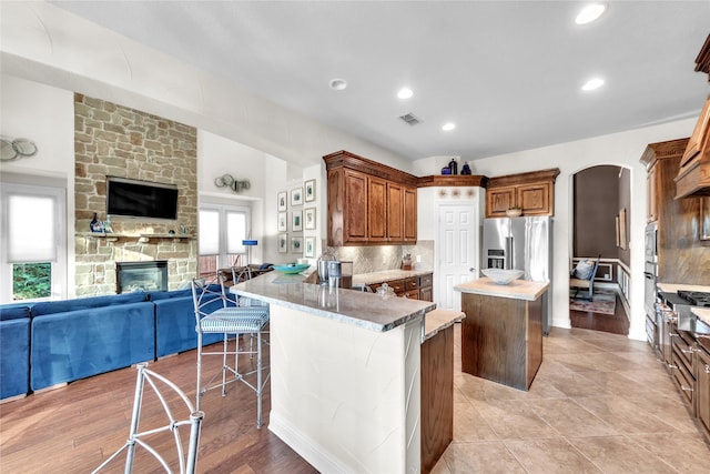 3040 N Camino Lagos, Grand Prairie, TX 75054 - kitchen with a kitchen breakfast bar, arched walkways, a center island, open floor plan, and a fireplace