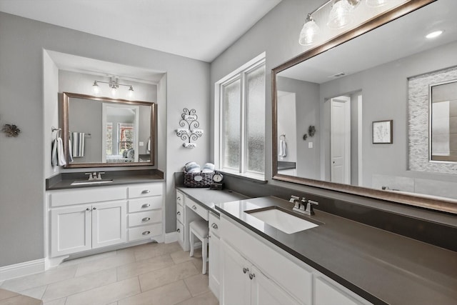 full bath featuring tile patterned floors, baseboards, two vanities, and a sink