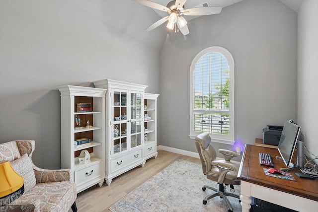 office space featuring ceiling fan, baseboards, high vaulted ceiling, and light wood-type flooring