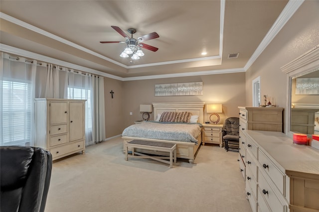 bedroom featuring crown molding, visible vents, ceiling fan, a tray ceiling, and light carpet