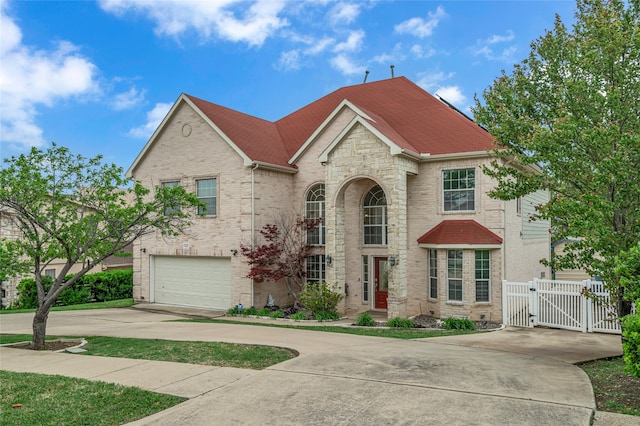 view of front of property featuring concrete driveway, an attached garage, brick siding, and a gate