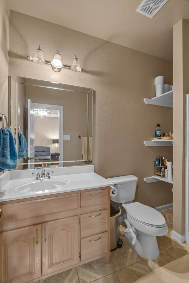 bathroom with a textured wall, visible vents, toilet, vanity, and tile patterned flooring