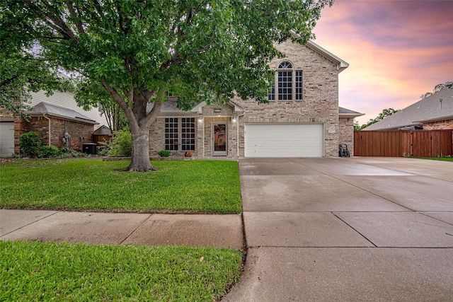 obstructed view of property with concrete driveway, fence, a yard, brick siding, and a garage