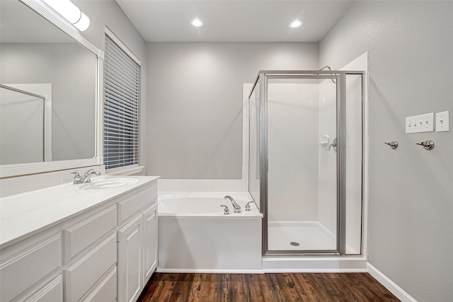 bathroom with wood finished floors, a shower stall, a garden tub, and vanity