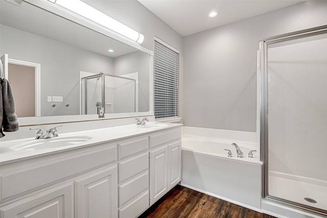 full bathroom featuring double vanity, wood finished floors, a shower stall, and a sink