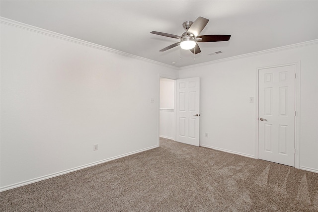 carpeted empty room with visible vents, a ceiling fan, ornamental molding, and baseboards