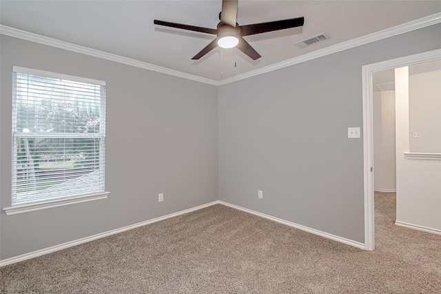 carpeted spare room featuring baseboards, visible vents, ornamental molding, and a ceiling fan