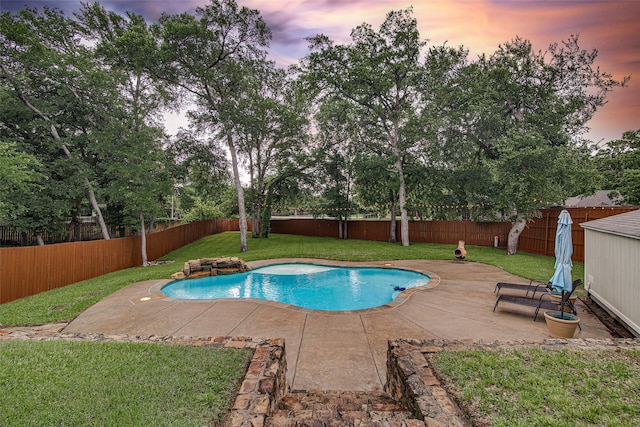 pool at dusk with a yard, a patio area, and a fenced backyard