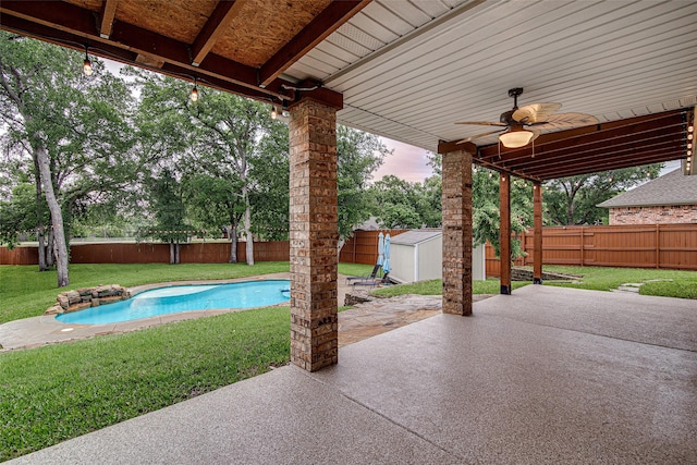 view of patio with an outdoor structure, a storage unit, ceiling fan, and a fenced backyard