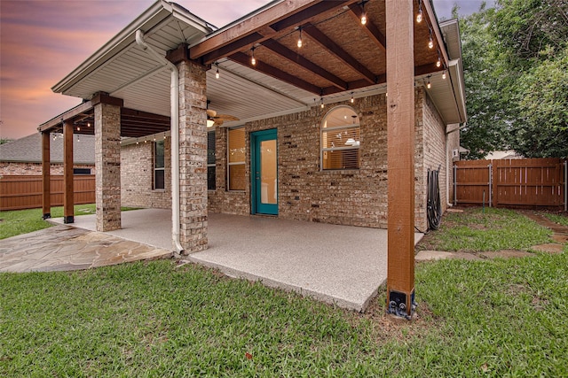 rear view of property featuring a lawn, fence, and a patio area