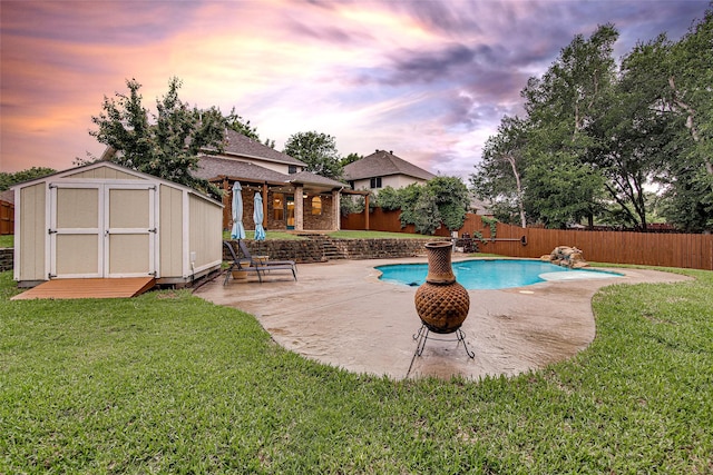 view of pool featuring a lawn, a storage shed, an outdoor structure, and a fenced backyard