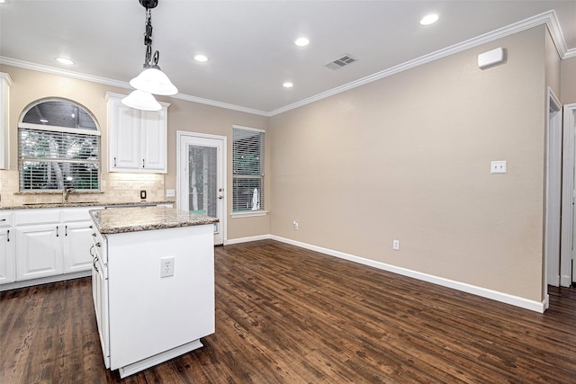 kitchen featuring crown molding, white cabinets, visible vents, a kitchen island, and dark wood-style floors