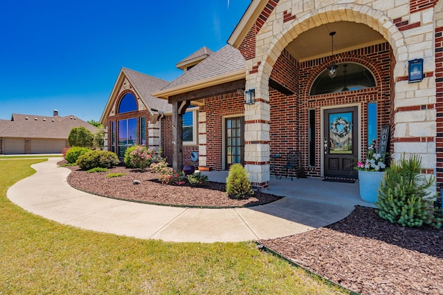 property entrance with brick siding, a shingled roof, and stone siding