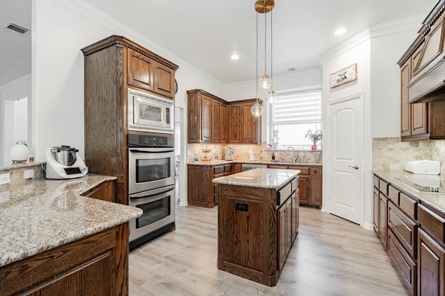 kitchen with a sink, decorative backsplash, visible vents, light stone counters, and appliances with stainless steel finishes