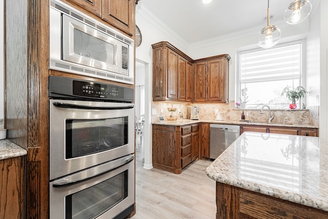 kitchen featuring brown cabinets, light stone counters, a sink, and appliances with stainless steel finishes