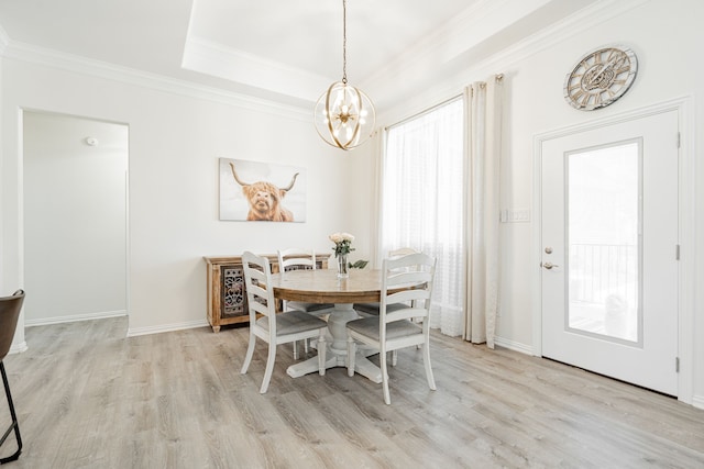 dining room with ornamental molding, light wood-style flooring, a chandelier, and baseboards