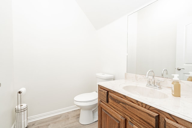 bathroom featuring baseboards, wood finished floors, toilet, and vanity
