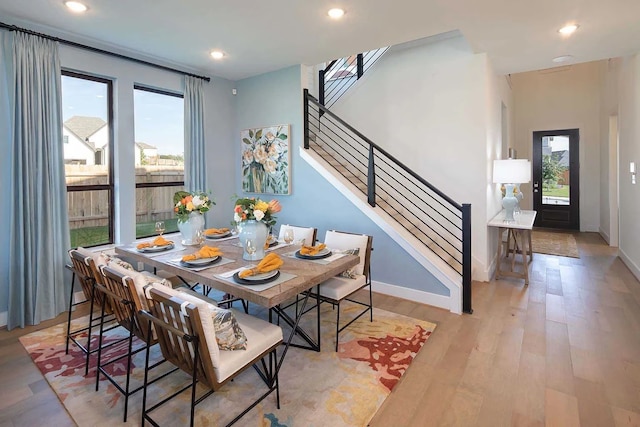 dining area featuring stairway, a healthy amount of sunlight, light wood-style floors, and recessed lighting