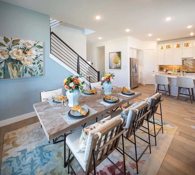 dining space featuring recessed lighting, stairway, light wood-style flooring, and baseboards