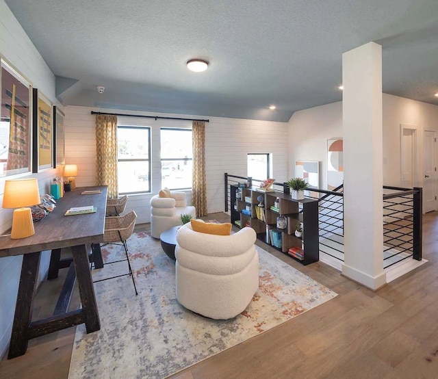 living area featuring an upstairs landing, baseboards, wood finished floors, and a textured ceiling