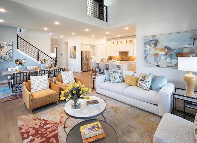 living area featuring baseboards, stairway, light wood-style floors, and recessed lighting