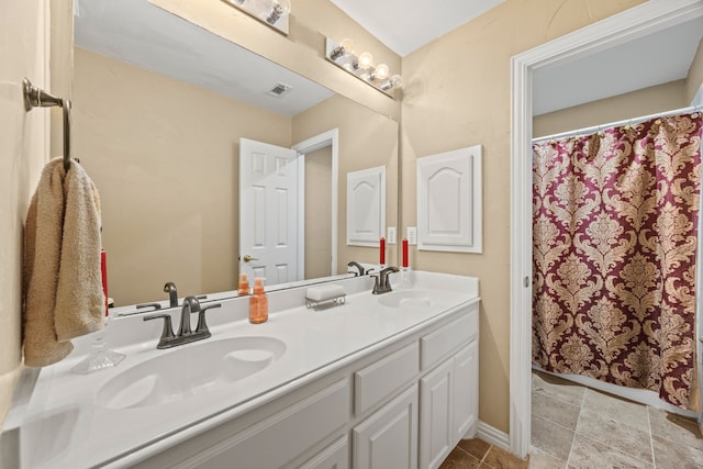 bathroom with double vanity, a sink, and visible vents