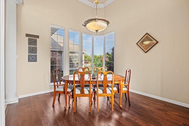 dining area with ornamental molding, decorative columns, a towering ceiling, baseboards, and dark wood-style floors