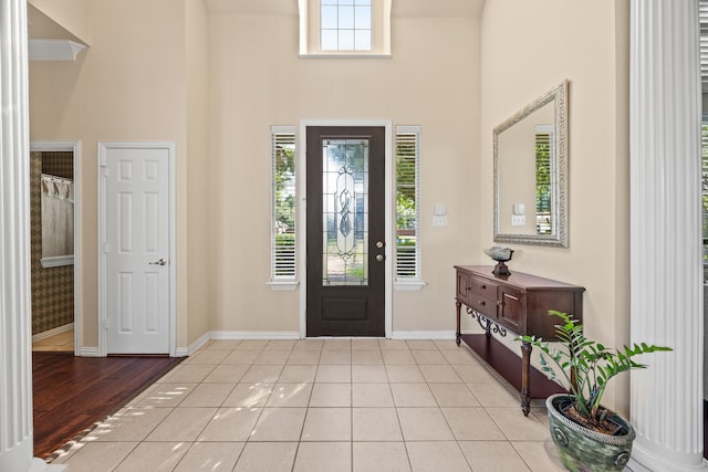 foyer featuring baseboards and a towering ceiling
