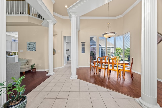 dining room with ornamental molding, decorative columns, a towering ceiling, baseboards, and light tile patterned floors