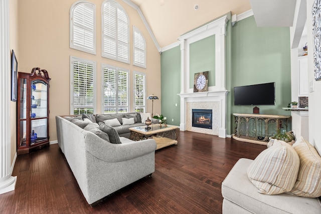 living area featuring high vaulted ceiling, a glass covered fireplace, baseboards, and dark wood-type flooring