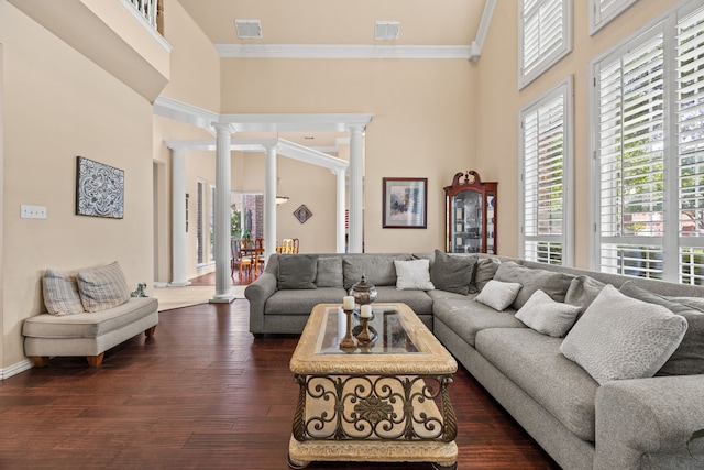 living area with visible vents, decorative columns, and a towering ceiling