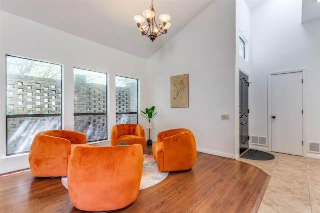 sitting room featuring a chandelier, high vaulted ceiling, wood finished floors, and visible vents