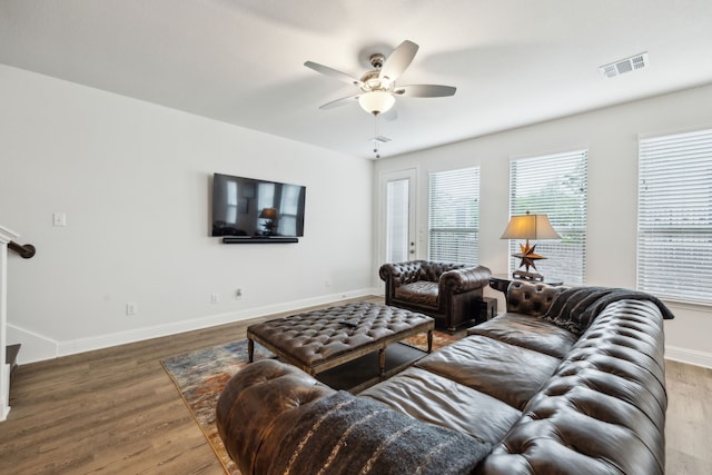 living room with wood finished floors, visible vents, a ceiling fan, and baseboards