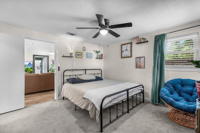 bedroom with visible vents, a ceiling fan, a textured ceiling, and carpet flooring