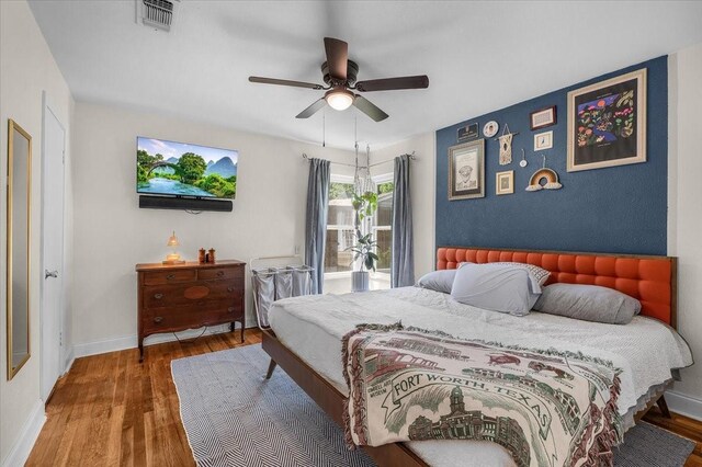 bedroom featuring baseboards, visible vents, wood finished floors, and a ceiling fan