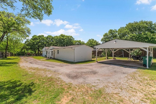 exterior space featuring dirt driveway, fence, and a detached carport