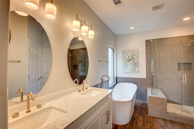 4001 Pineoak Ln, Denton, TX 76210 - bathroom featuring a soaking tub, a stall shower, double vanity, wood finished floors, and recessed lighting