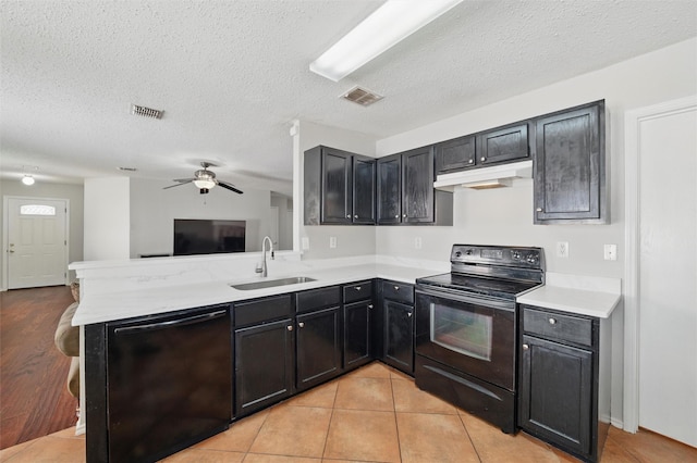 kitchen with a sink, under cabinet range hood, black appliances, visible vents, and open floor plan