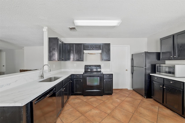 kitchen with a textured ceiling, light tile patterned floors, a sink, light countertops, and black appliances
