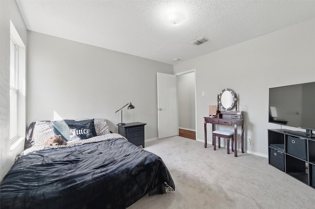bedroom featuring a textured ceiling, visible vents, carpet, and baseboards