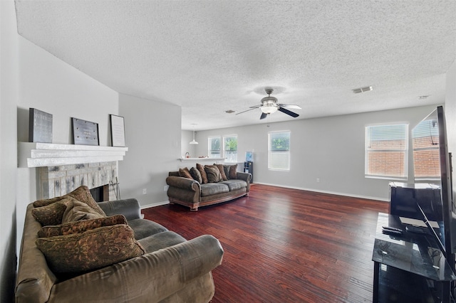 living room featuring baseboards, visible vents, wood finished floors, and a fireplace