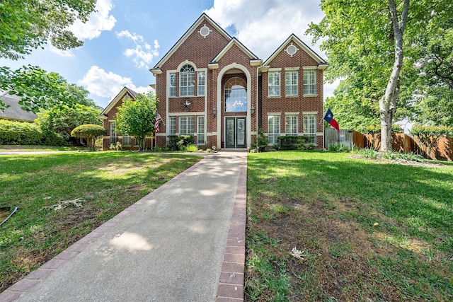 view of front of house featuring a front yard, fence, and brick siding
